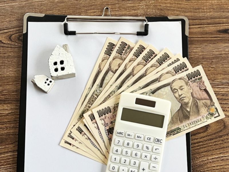 クリップボードの上の一万円札と電卓・住宅費用イメージ
