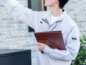 作業服の職人が外壁を指差しチェック・現地調査イメージ